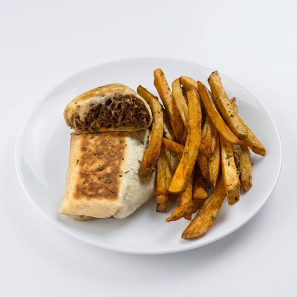 A cut burrito filled with meat and cheese, served with seasoned french fries on a white plate.